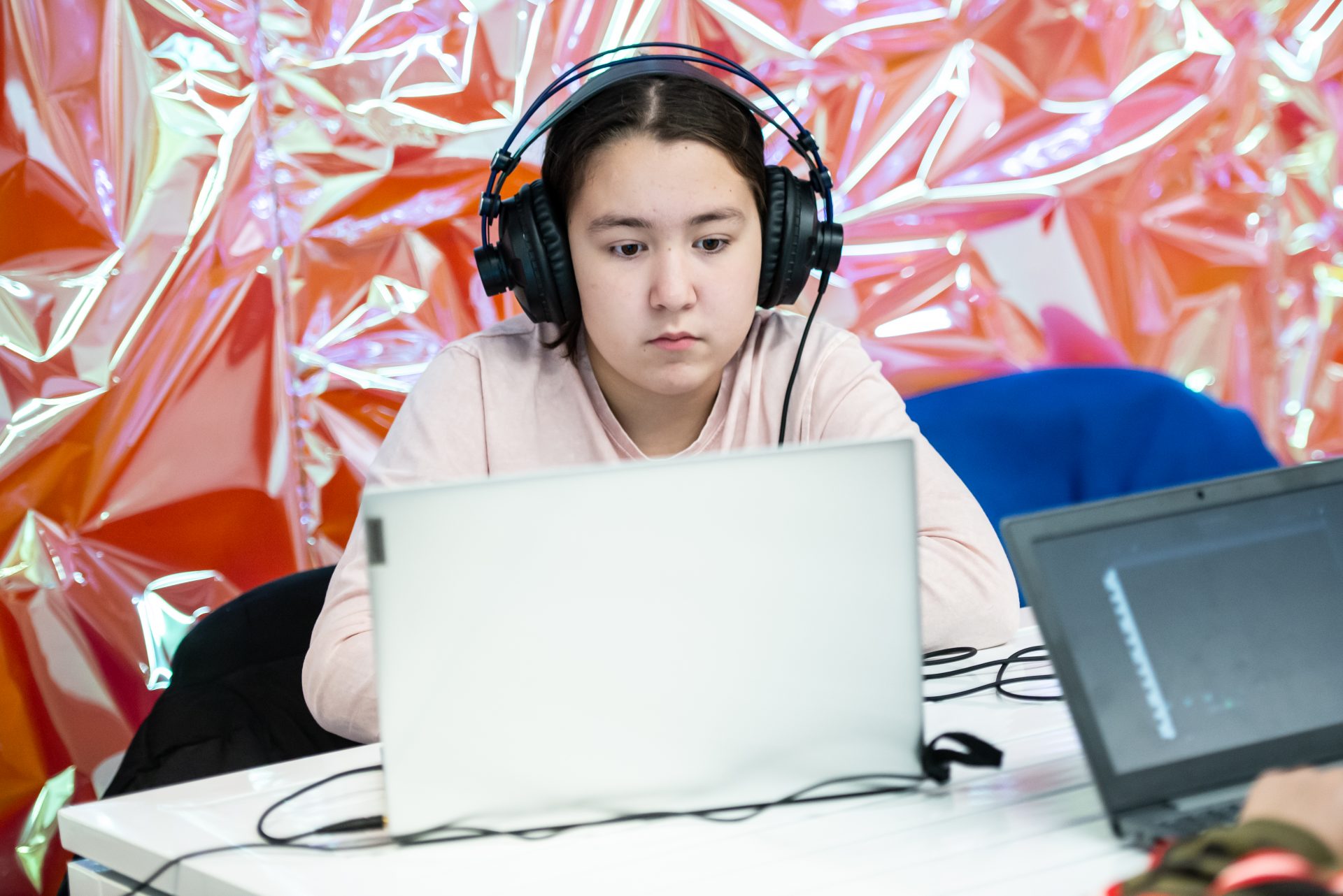 Image shows young person on computer with headphones.