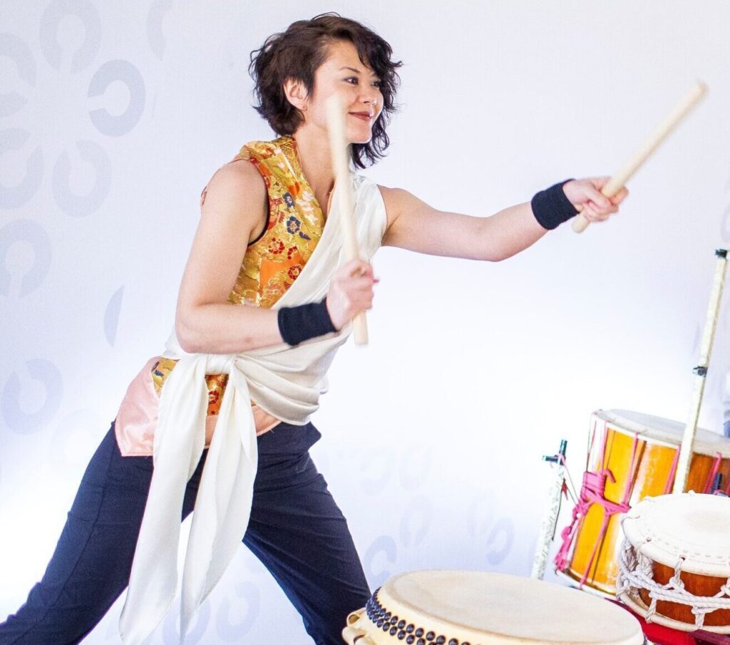 person holding drum sticks in the air with three drums